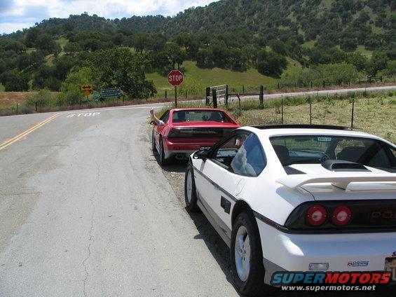 White 1984 Pontiac Fiero parked on a rural road, rear 3/4 view
