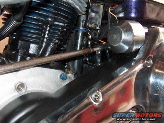 Close-up of motorcycle engine components, including cylinders and chrome parts. Watermark reads SUPERMOTORS