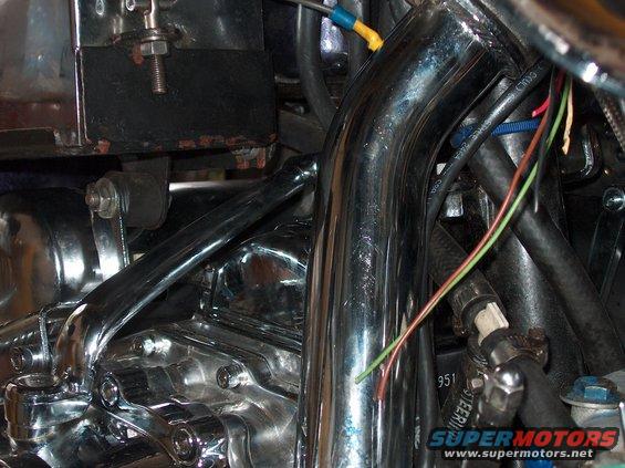 Close-up of chrome exhaust pipes and engine components on a motorcycle, with visible wiring