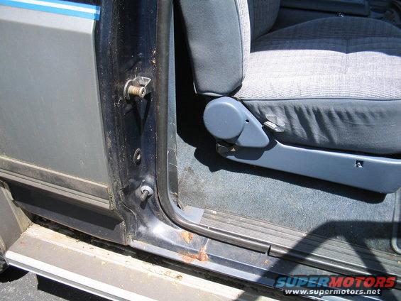 Gray fabric seat and dark blue interior door panel with rust on the door sill of a 1989 Ford Bronco