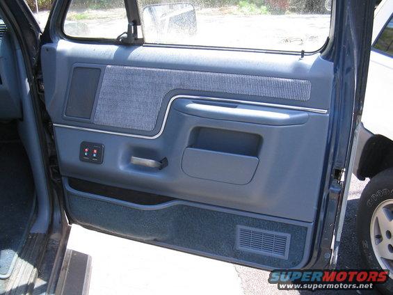 Blue interior door panel with fabric insert, speaker grille, and power window controls
