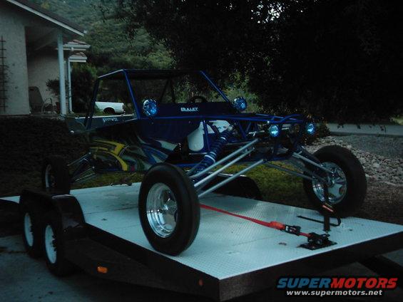 Blue dune buggy with custom graphics on a flatbed trailer