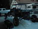 1978 Ford Bronco - A custom dune buggy with a prominent roll cage and exposed engine is parked outdoors next to a white SUV.