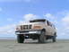 1988 Ford C-250 (Centurion Conversions) - This tan Ford SUV, likely from the early 1990s, is parked on a sandy beach under a partly cloudy sky. The image is dated May 2, 2005.