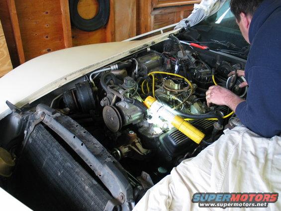 White 1981 Chevrolet Corvette engine bay with a person working on the engine