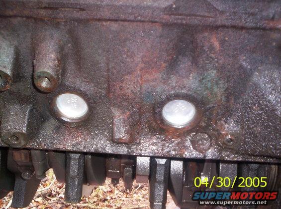 Close-up of an engine block with visible crankshaft and two frost plugs. Date stamp reads 04/30/2005