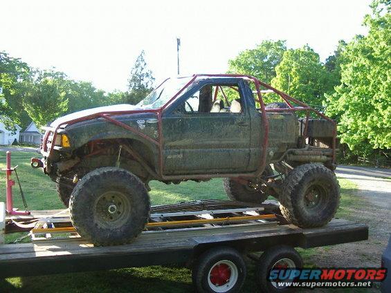 Customized pickup truck with a roll cage and large tires on a trailer