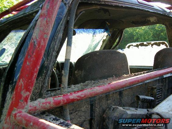 Mud-covered interior with roll cage and cracked windshield