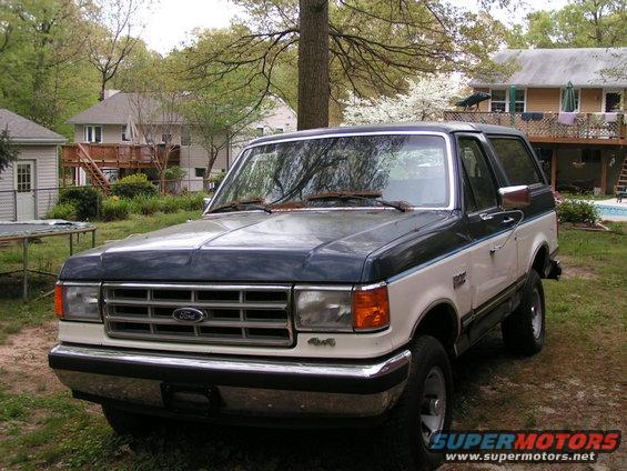1987 Ford Bronco parked in a yard with houses in the background