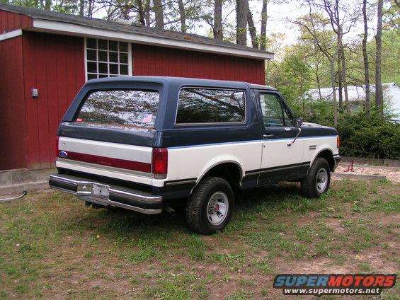 1987 Ford Bronco parked in front of a red building