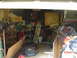 1985 Ford Bronco - This image depicts a disorganized garage space filled with various items, including a lawnmower and tools, with a timestamp in the corner.