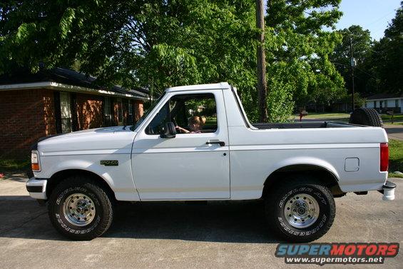 White Ford Bronco with a child in the driver's seat, seen from the side