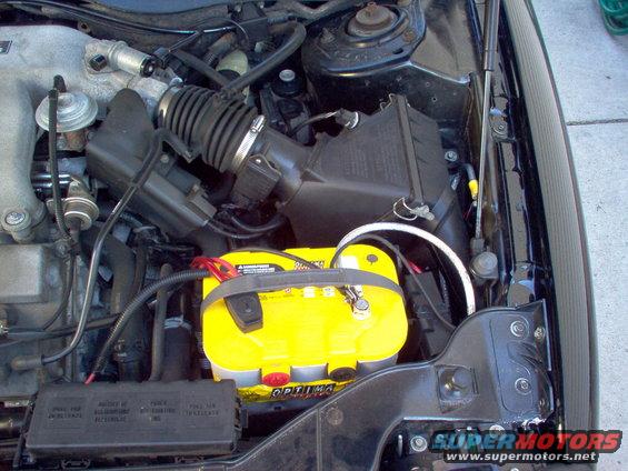 Engine bay showing air intake, fuse box, and a yellow Optima battery with red terminals