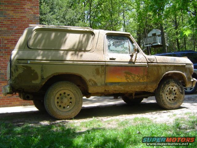 Mud-covered 1978 Ford Bronco, side view, showing rust and faded paint