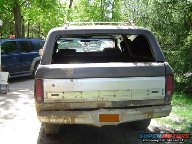 Rear of a muddy 1978 Ford Bronco with a blue SUV parked nearby