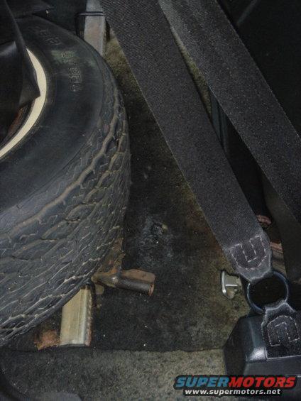 Spare tire and black seatbelt in a vehicle's cargo area