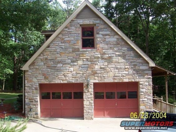 Stone-faced garage with two red doors and a date stamp