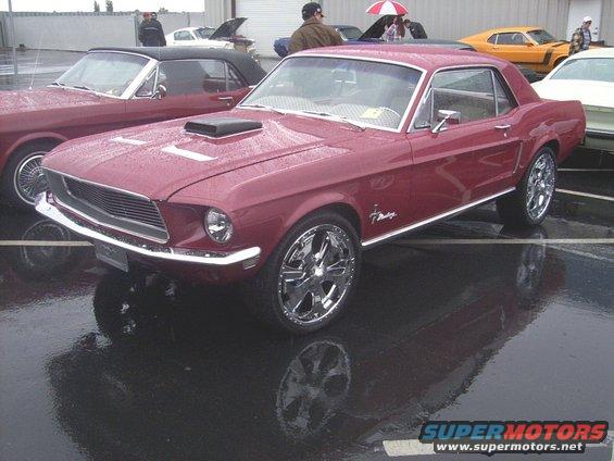 Red 1967 Mustang coupe with hood scoop and chrome wheels