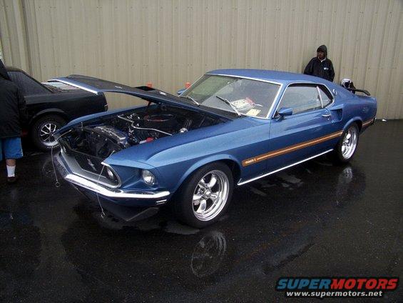 Blue classic Ford Mustang with hood open, parked next to a black car