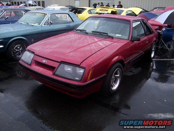 Red Ford Mustang with GT5 emblem on front fender, parked next to a blue Mustang