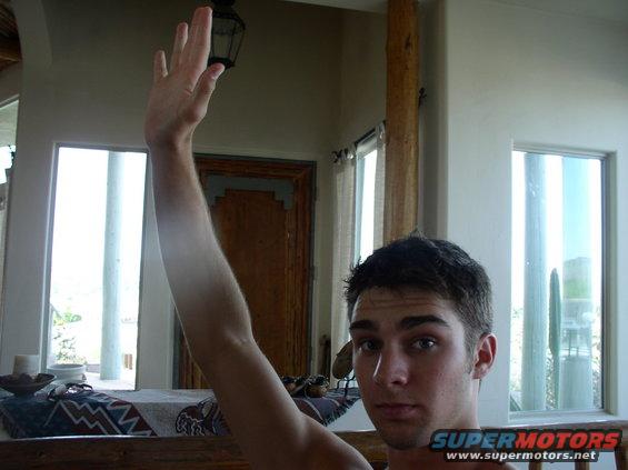 Man with arm raised, indoor setting with windows and furniture