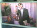 1990 Ford Bronco - A television displays a scene with a man in a tuxedo and a young woman, set against a backdrop of floral arrangements and curtains.