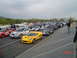 1999 Ford Crown Victoria - Cars lined up on a race track, possibly before an event, with spectators in the background.