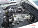 1999 Ford Crown Victoria - Close-up of a V8 engine bay a supercharger and other engine components. Another vehicle is partially visible.