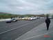 1999 Ford Crown Victoria - A white police car, likely a Ford Crown Victoria, is lined up with other vehicles on a race track.
