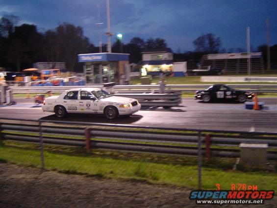 White 1999 Ford Crown Victoria race car with racing decals, seen from the front-right