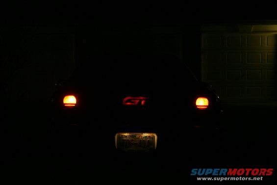 car's rear with taillights on and a GT badge