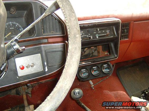 1987 Ford Bronco interior showing dashboard, steering wheel, gear shifter, and aftermarket gauges