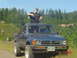 1988 Ford Ranger - A person stands through the sunroof of a blue 1984 Toyota pickup truck parked outdoors.