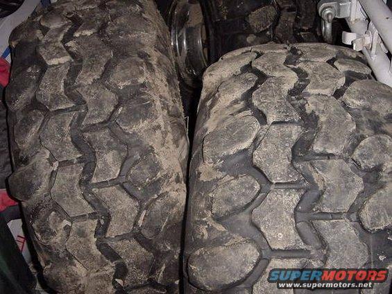 Two muddy off-road tires with aggressive tread patterns are shown up close
