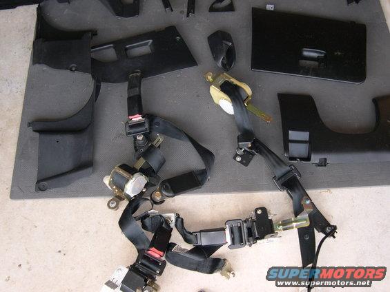 Seat belts and black plastic interior trim pieces laid out on a surface