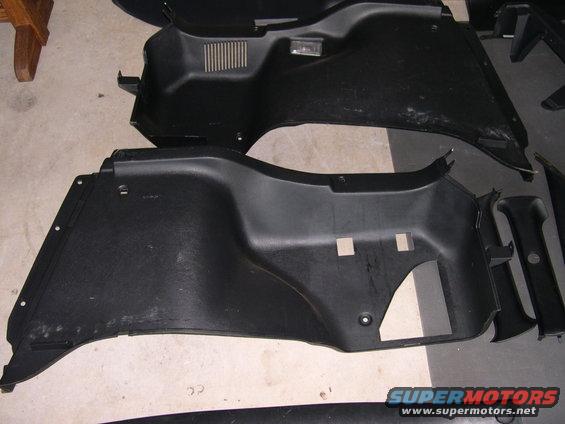 Black plastic car interior trim panels, some with vents and cutouts, laid out on a floor