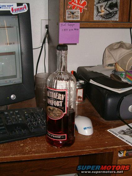 Bottle of Southern Comfort on a desk next to a computer monitor and keyboard