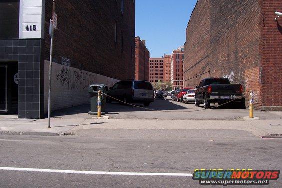 Alley with parked cars and a black pickup truck. Building number 415 visible