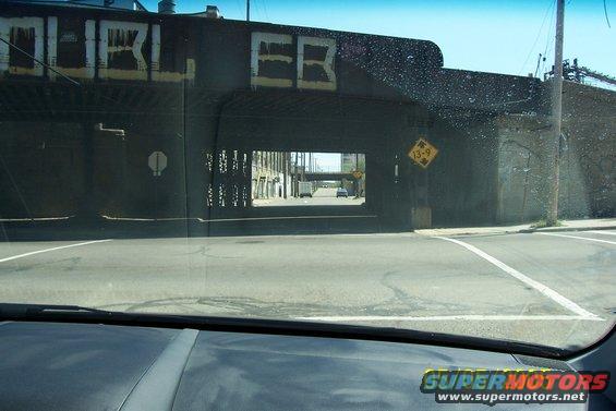 Interior view through windshield of a car driving under a graffiti-covered overpass