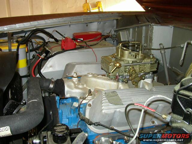 Engine bay showing carburetor, battery, and wiring