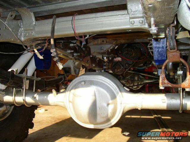 Undercarriage view showing leaf springs, differential housing, and suspension components. Some wiring and mechanical parts are visible
