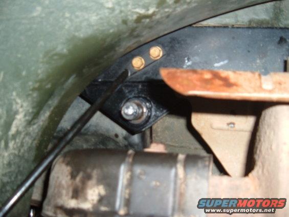 close-up of metal bracket and exhaust pipe under a vehicle