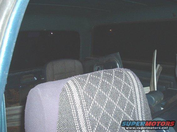 Back seats of a vehicle, looks like a truck or SUV. Dark interior with patterned seat covers