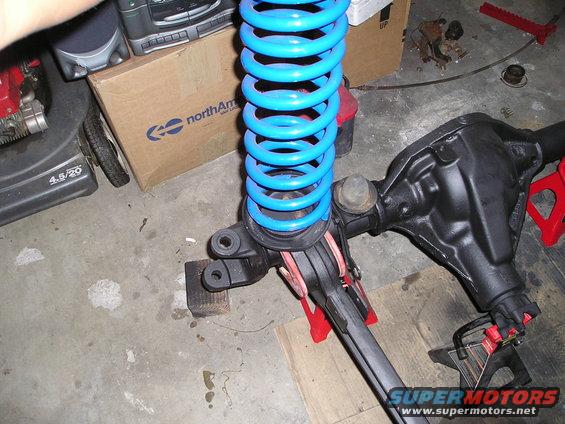 front axle assembly with a bright blue coil spring on jack stands
