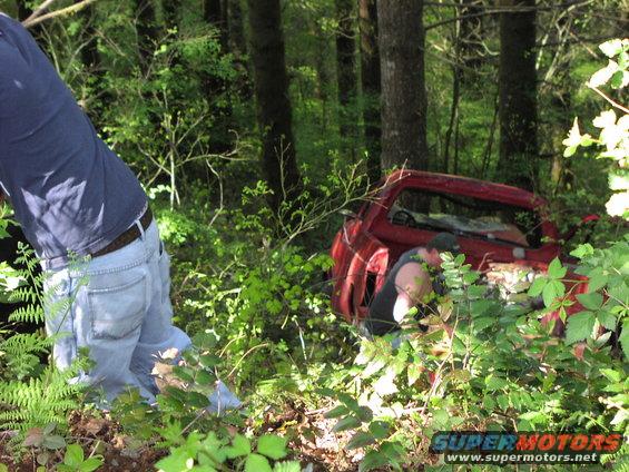 red pickup truck in woods, hood open, people working on it