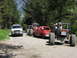 1993 Ford Bronco - Multiple off-road vehicles are parked on a dirt road surrounded by trees.