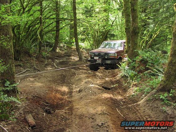 1993 Ford Bronco winching itself out of a muddy forest trail