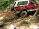 1993 Ford Bronco - This maroon and white Ford Bronco navigates a challenging dirt trail with large tires and a rear-mounted spare.