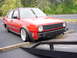 1998 Volkswagen Jetta - Red Volkswagen Jetta on a tow truck, front bumper removed.