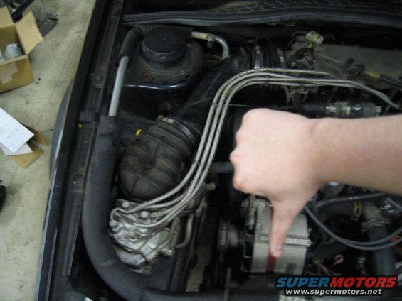 Car engine bay with a hand giving a thumbs down gesture. "SUPERMOTORS www.supermotors.net" text is visible